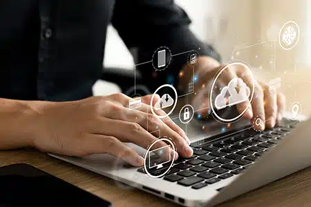 Stockbild einer Labtoptastatur mit zwei Händen auf der Tastatur. Symbolisch kann man auch noch sowas wie eine Cloudanwendung sehen
